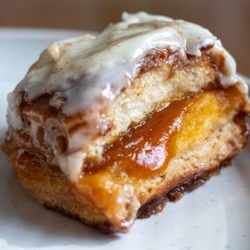 a singular hawaiian roll cinnamon roll on a white plate.