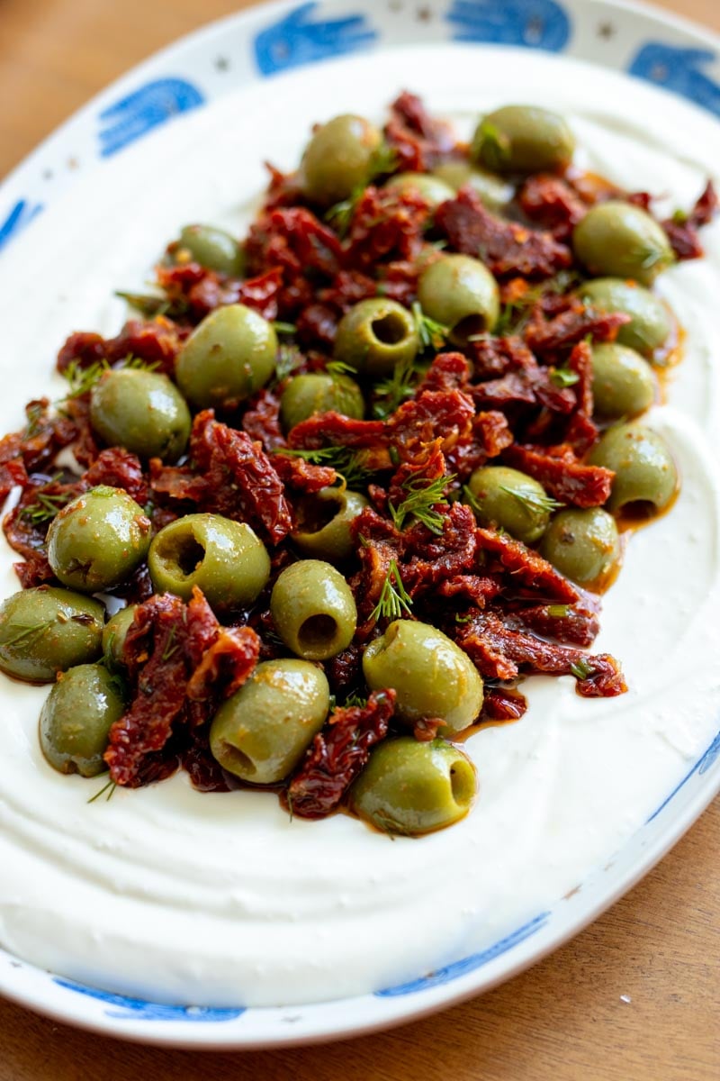 a white and blue platter topped with a colorful mediterranean dip on top.