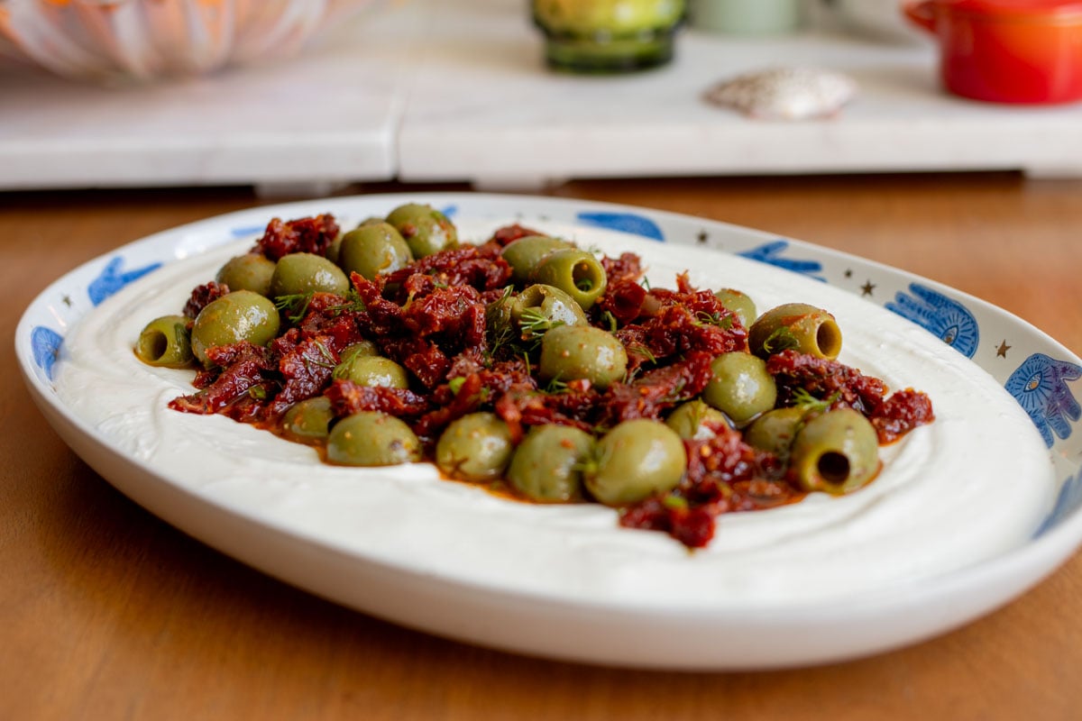 a white plate with blue evil eyes on it topped with a colorful mediterranean dip.